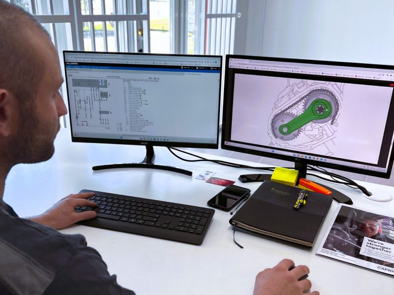 Amped Autotech mechanic reviewing european car diagnostics on a computer.